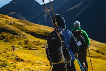 Hikers trekking the Lares Trail through golden Andean highlands, with grazing alpacas and towering mountains in the background.